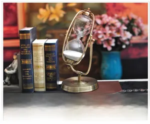 Detail einer Vintage-Sanduhr aus Bronze mit weißem Sand auf Büchern platziert