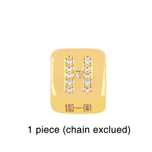 Macro shot of gold square pendant with cubic zirconia letter H and hollow side detail