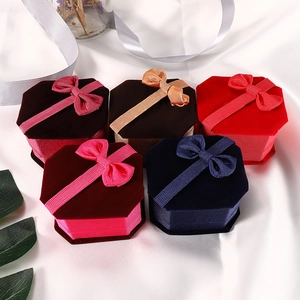 Hexagonal velvet jewelry gift boxes with ribbon bows on white silk background