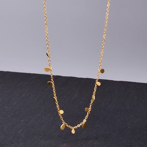 Close-up of minimalist golden chain necklace with small circular sequin pendants