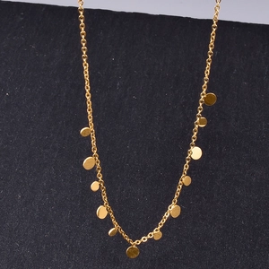 Minimalist gold chain necklace with round disk pendants displayed on dark background