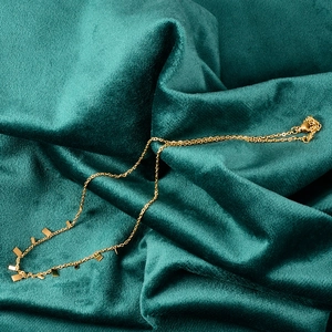 Chic gold-plated necklace with rectangular pendants displayed on green velvet fabric