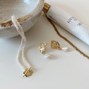 Detailed shot of baroque pearl earrings and necklace with gold-plated metal flower clasp