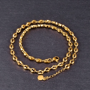 Detailed view of gold coffee bean chain necklace with lobster clasp and round logo tag
