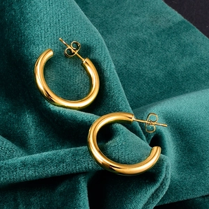 Detail shot of chunky gold C-shaped hoop earrings on elegant green velvet fabric