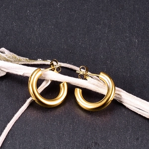 Detailed view of polished gold C-shape hoop earrings on a decorative branch