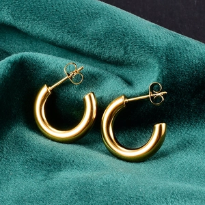 Close-up of polished gold hoop earrings on dark green velvet background with mirror shine