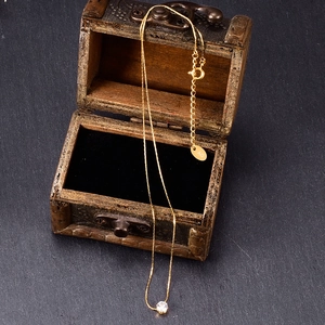 Detailed macro view of 18K gold plated titanium steel necklace with zircon in a wooden box