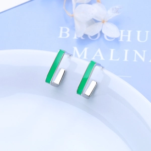Minimalist square green enamel stud earrings with silver borders on a white porcelain dish