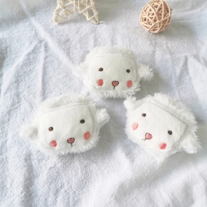 Three cute plush white sheep brooches with pink blush on a soft white fabric background