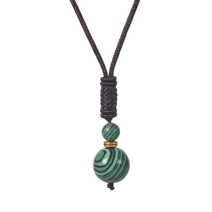 Macro shot of green malachite beads and golden spacer on handcrafted brown woven cord necklace