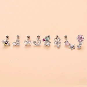 Surgical steel stud earrings set with butterfly and moon designs on pink background