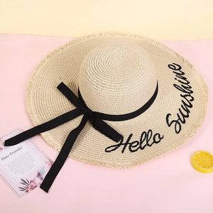Detail of wide brim straw hat with Hello Sunshine embroidery and black ribbon bow