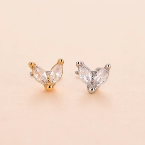 Macro detail of gold and silver L-shaped nose studs with marquise-cut cubic zirconia