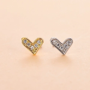 Detail of heart stud earrings in gold and silver finish with sparkling zircon stones