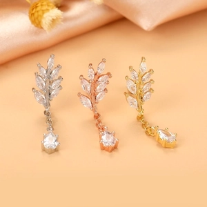 Detailed macro view of leaf-shaped ear studs in silver, rose gold, and gold finishes