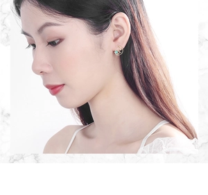 Close-up of star and moon stud earrings in gold with blue details on a model's ear