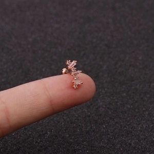 Makro-Detail des roségoldenen Knorpel-Ohrsteckers mit Zirkonia auf einem Finger