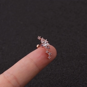 Nahaufnahme eines sternförmigen Piercings aus Roségold mit Zirkon-Inlays auf der Fingerspitze