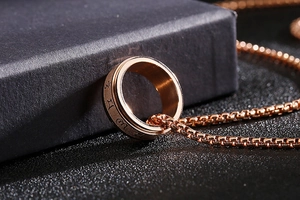 Close-up of rose gold spinning ring with 520 1314 engraving and matching box chain necklace