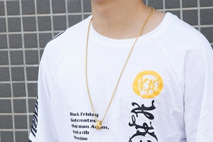 Close-up of a rotating Sanskrit mantra titanium steel ring and gold chain necklace set