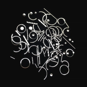 Silver metallic nail art studs in mixed shapes including circles and lines on black background
