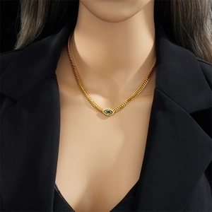 Vintage gold wheat chain necklace featuring a blue evil eye pendant on a female model