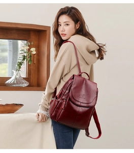 Detail of wine red leather backpack showing flip-top design and textured side pocket