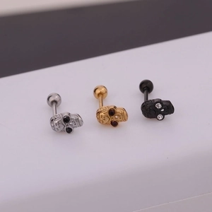 Macro detail of skull stud earrings in silver, gold, and black with barbell screw backs