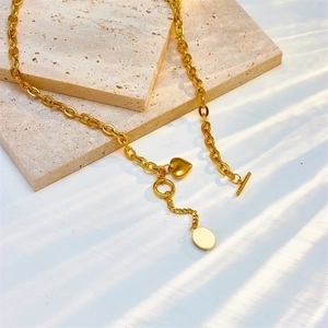 Gold chunky chain necklace with heart pendant and OT clasp on a textured stone base