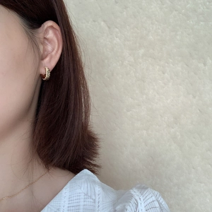 Close-up of a model wearing a gold twisted rope hoop earring in 925 sterling silver