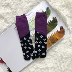 Detail view of Tabi socks with purple and black patchwork and white floral patterns
