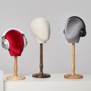 Three mannequin head stands in red, cream, and grey with fabric finish and solid wood base