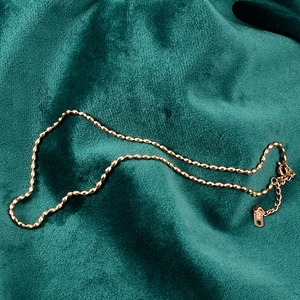 Detail shot of 18K gold bead chain necklace with adjustable clasp on green velvet