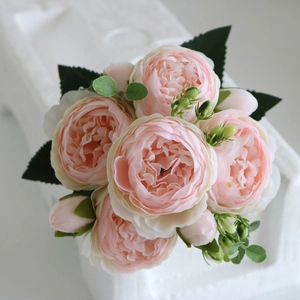 Close-up of pink peony silk flower bouquet with green leaves for wedding decor
