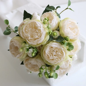 Macro shot of artificial cream peonies and roses bouquet with green leaves and buds