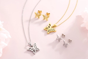 Macro shot of silver and gold hollow butterfly pendant necklace and matching stud earrings