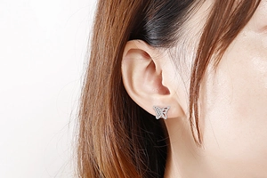 Close-up of a silver hollow butterfly stud earring worn on a model's earlobe