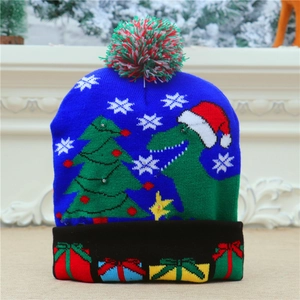 Detail of blue knitted Christmas hat with green dinosaur, tree and colorful gift patterns