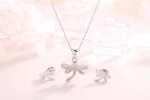 Elegant silver dragonfly jewelry set with necklace and earrings on soft pink backdrop