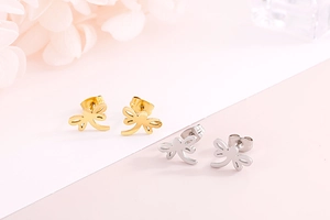 Detailed close-up of gold and silver dragonfly stud earrings on a floral background