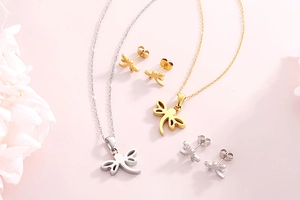 Elegant gold and silver dragonfly necklaces and earrings set on a soft floral background
