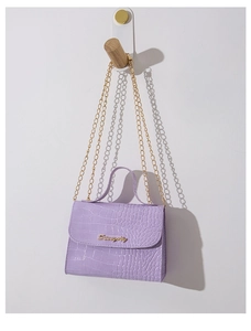 Dettaglio borsa viola a motivo coccodrillo con logo dorato e catena su gancio