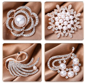 Macro detail of elegant flower and swan brooches with pearls and crystals on silk fabric