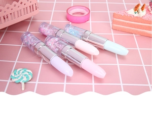 Detailed close-up of cute lipstick-shaped liquid glitter pens in pastel colors on grid background