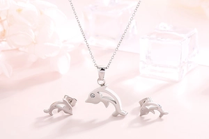 Detail of silver dolphin jewelry set with necklace and earrings on a pink background