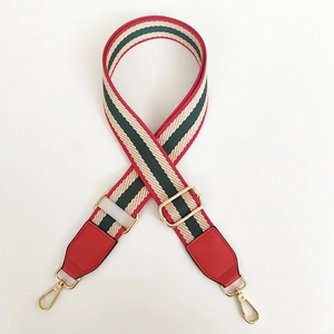Adjustable woven handbag strap with red and green stripes and gold metal hardware