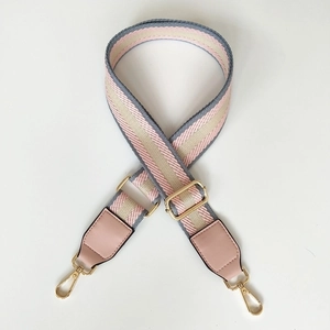 Detail of adjustable canvas bag strap with pink and grey stripes and gold hardware