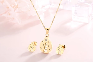 Detail shot of golden ladybug necklace and stud earrings set with sparkling rhinestones
