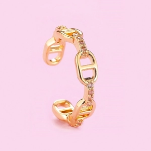 Macro shot of gold D-chain ear cuff with micro-pave pink zircon stones on pink backdrop
